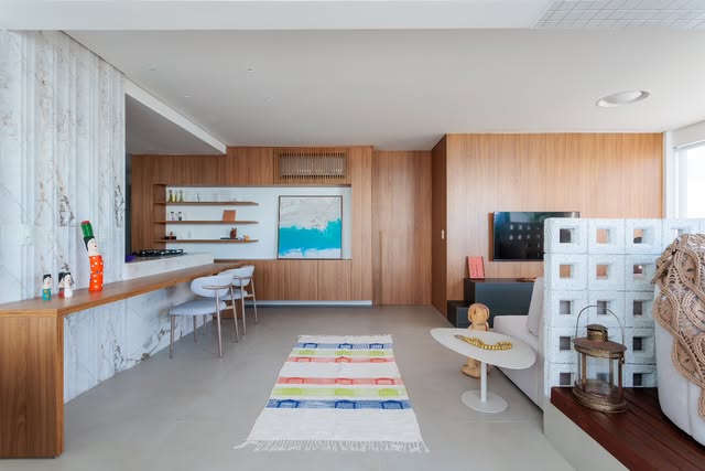 Ambiente integrado de estar e jantar com painéis de madeira, sofá claro e luz natural